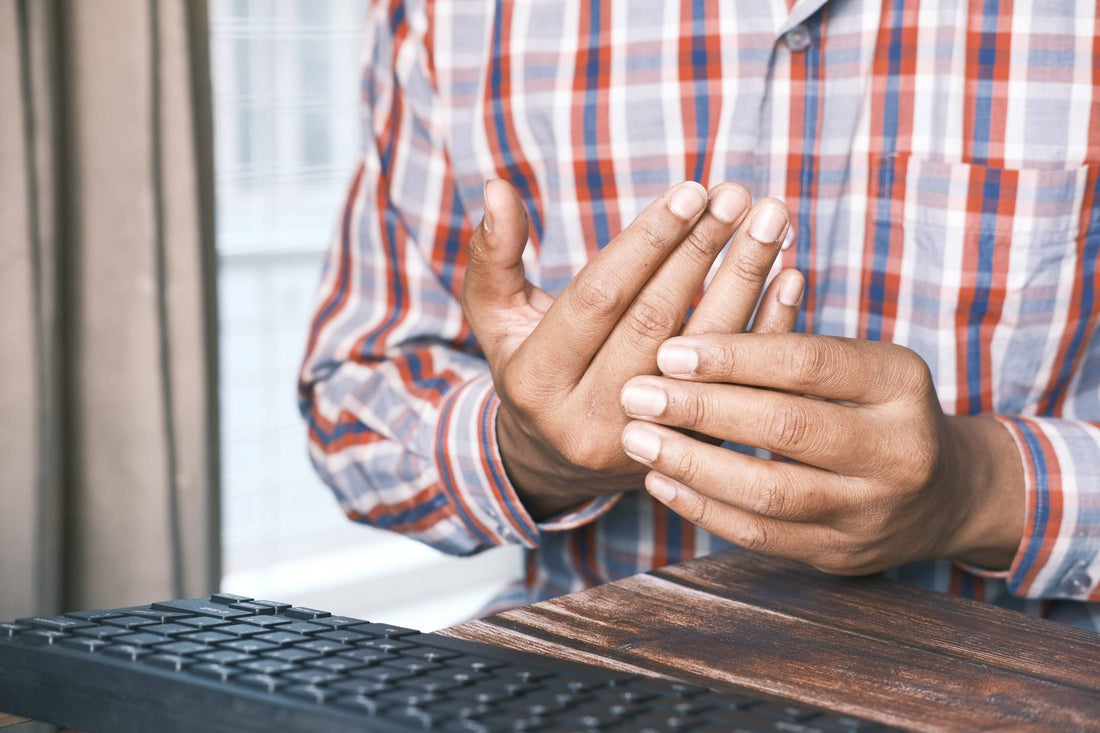 Man Rubbing Painful Hands at Desk