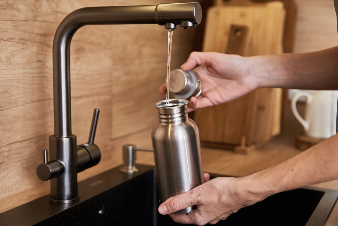 Person Filling Water Bottle From Tap in Kitchen