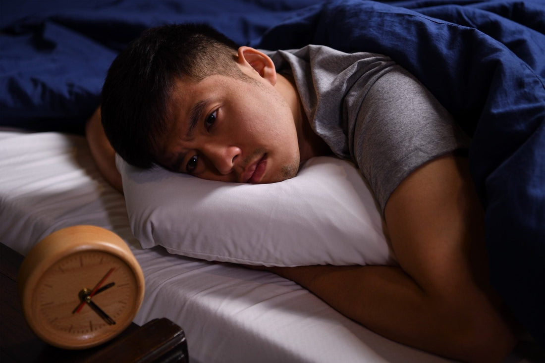 Man Lying Awake in Bed Beside an Alarm Clock